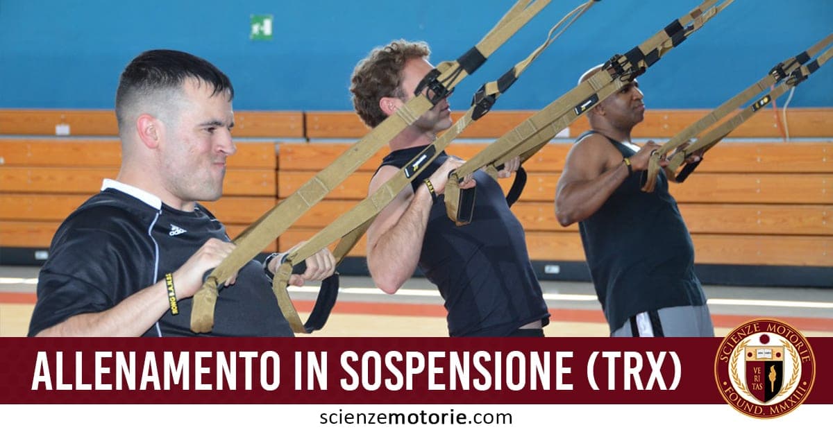 Tre persone eseguono esercizi con cinghie TRX in palestra, utilizzando l’allenamento in sospensione.