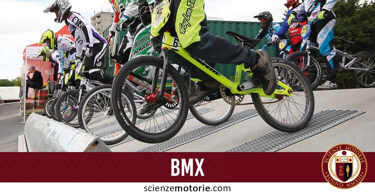Gruppo di ciclisti BMX in attesa sulla rampa di partenza, con caschi e abbigliamento protettivo, scena di gara o allenamento.