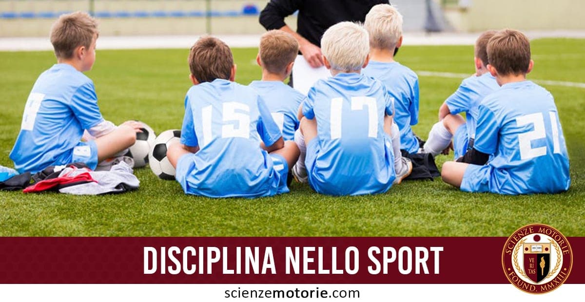 L'immagine raffigura sei bambini con magliette azzurre numerate seduti su un campo da calcio in erba sintetica, mentre un adulto – probabilmente un allenatore – parla con loro. Accanto ai bambini ci sono alcuni palloni da calcio. In basso, una barra rossa con la scritta "DISCIPLINA NELLO SPORT" e il logo di "Scienze Motorie"