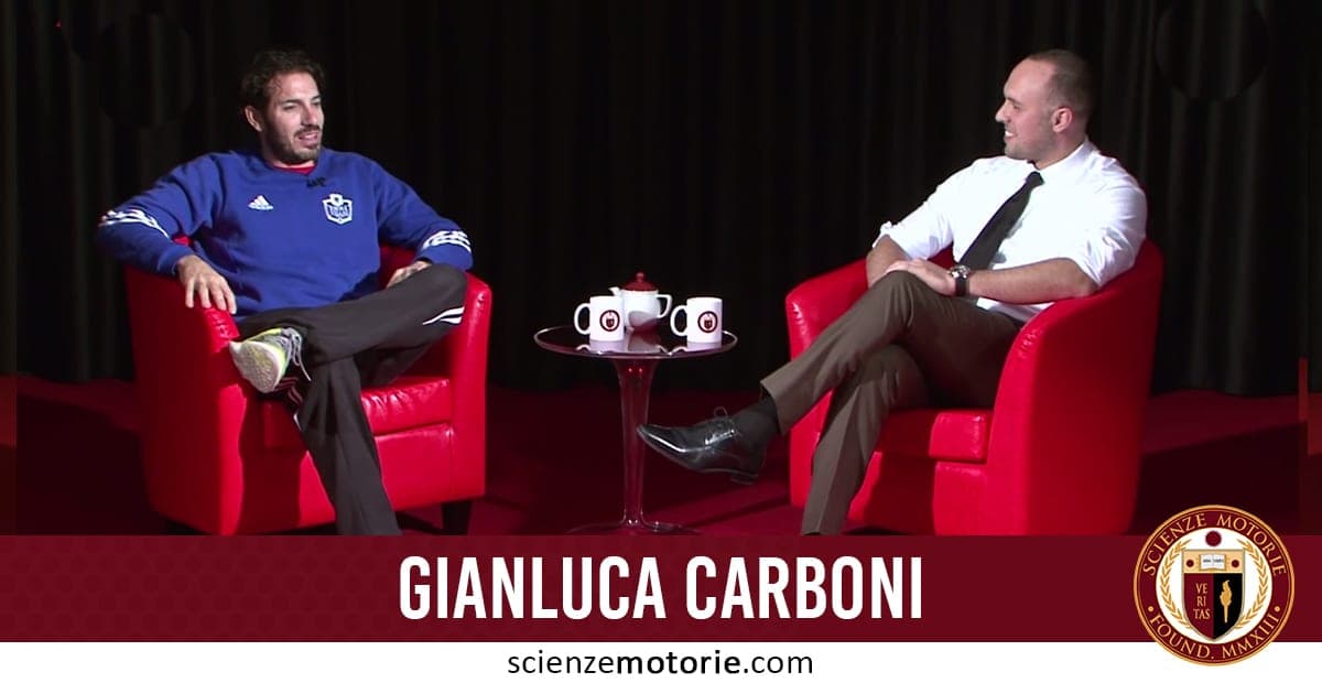 Foto di Gianluca Carboni con felpa blu e Giacomo Catalani in camicia bianca e cravatta, seduti su poltrone rosse durante un’intervista per Scienze Motorie.