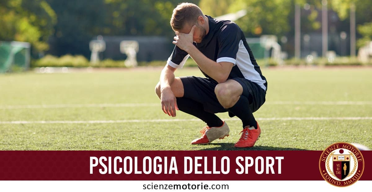 L'immagine mostra un atleta seduto su un campo sportivo, con la testa china e una mano sul volto, in atteggiamento pensieroso o stressato. Indossa una divisa sportiva nera con dettagli bianchi e scarpe sportive arancioni. Sotto l'immagine c'è una scritta che dice "PSICOLOGIA DELLO SPORT" ed il logo di Scienze Motorie